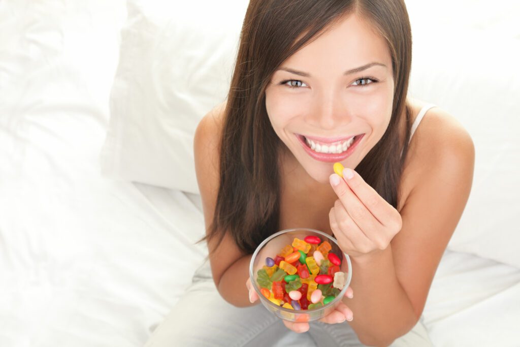 Woman eating gummy bears in a clear glass bowl