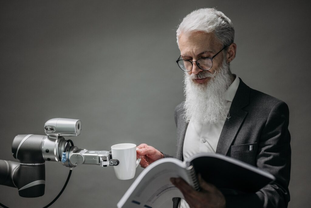 Old man holding a book and a machine partly holding his cup